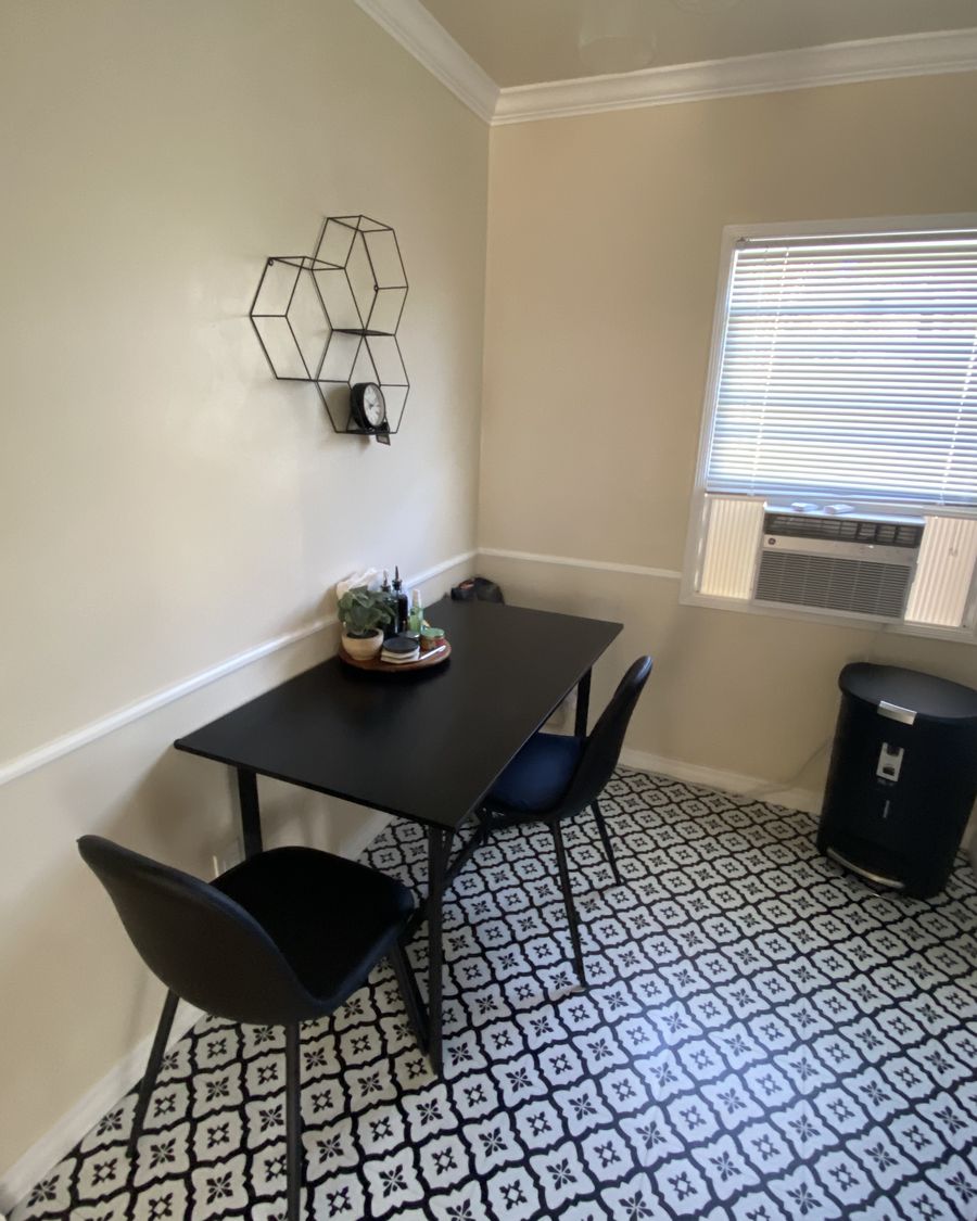 Dining nook reset between guests in a Los Angeles rental: table wiped and styled with a small plant, chairs pushed in, patterned tile floor mopped.