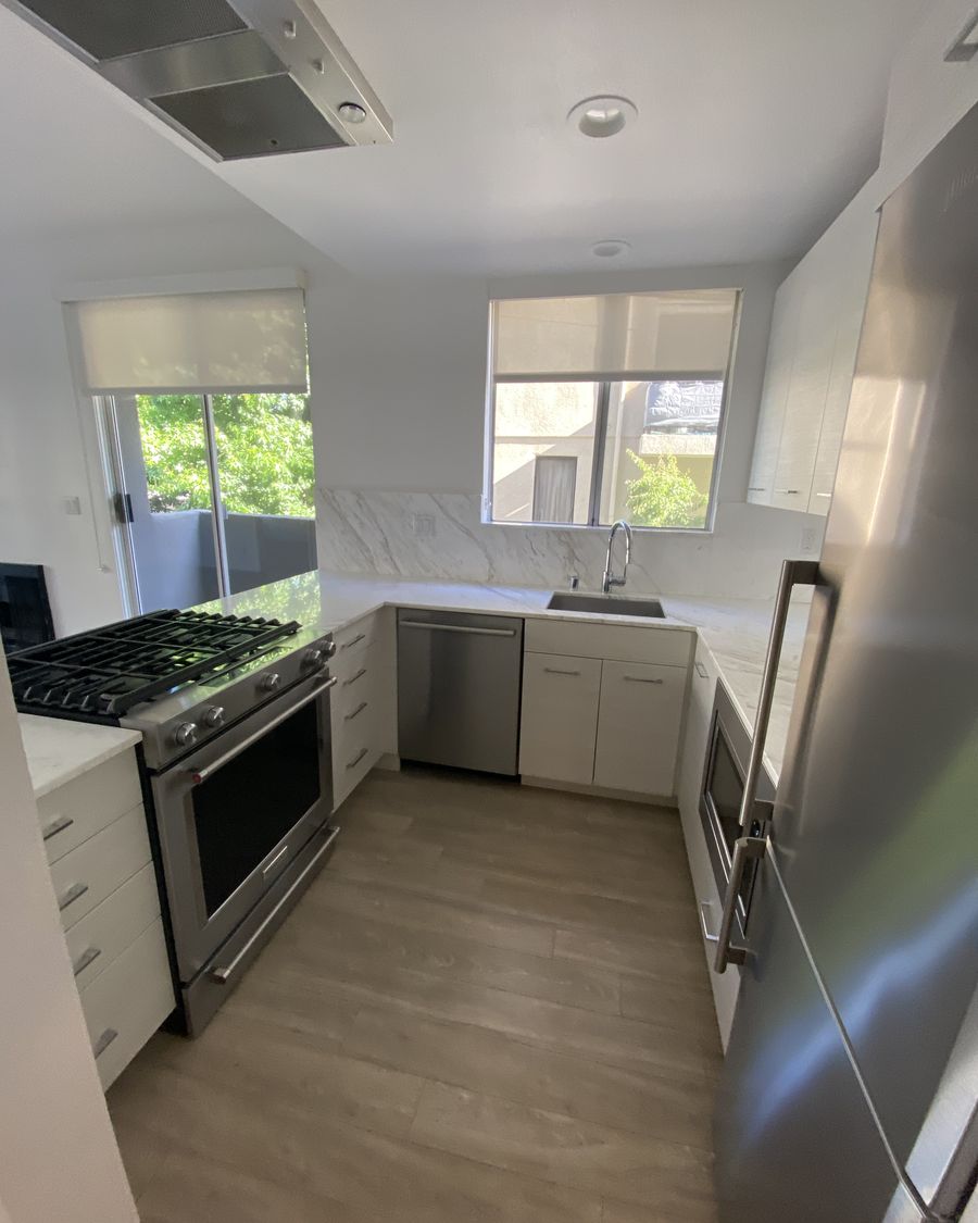 Rental kitchen after an Airbnb turnover clean in Los Angeles: marble counters wiped clear, sink empty and dry, gas stovetop clean, floors swept.
